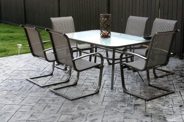 A dark-gray stamped concrete patio with a table and chairs in Aurora IL.